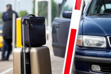 Walizki stoją przy słupku na parkingu lub przy wjeździe bramkowym, obok stoi granatowy samochód osobowy z otwartymi drzwiami.
